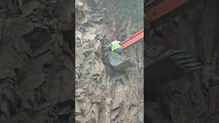 A worker on the bucket of a crawler excavator pulls something out of a rock with the bucket [upl. by Chas582]