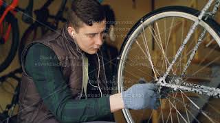 Skilled mechanic is rotating bicycle wheel checking mechanism and turning treadle while fixing bike [upl. by Wenonah]