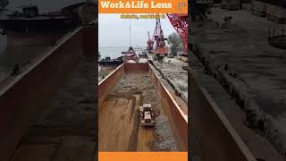 A bulldozer pushes stones into piles in a ships hull for a crane to load onto trucks [upl. by Craddock716]